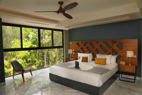 a bedroom with a bed and a chair and windows at Panther Bay Boutique Hotel in Akumal