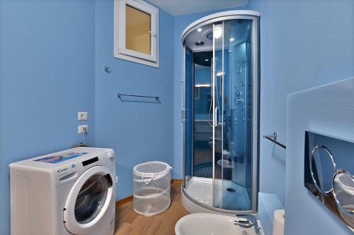 a blue bathroom with a washing machine and a toilet at CASA DEI LIMONI in Gardone Riviera