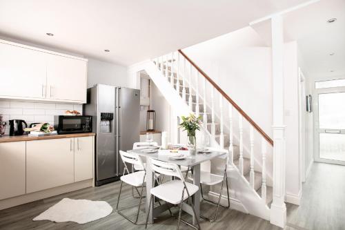 a white kitchen with a white table and chairs at Bijoux Plymouth Cottage - Sleeps 6 - By Habita Property in Plymouth