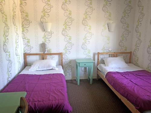 - 2 lits dans une chambre avec des draps violets et une table dans l'établissement Les Closeaux Phil, à Mortain