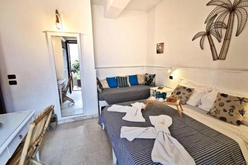 twee bedden in een kamer met een spiegel en een bank bij Loft Palm Beach - 100 metri dalla spiaggia di sabbia bianca e dal mare in Fontane Bianche