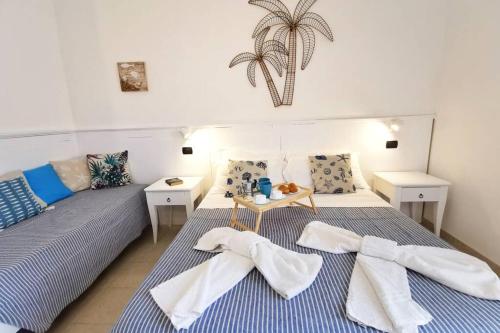 een slaapkamer met twee bedden met handdoeken erop bij Loft Palm Beach - 100 metri dalla spiaggia di sabbia bianca e dal mare in Fontane Bianche