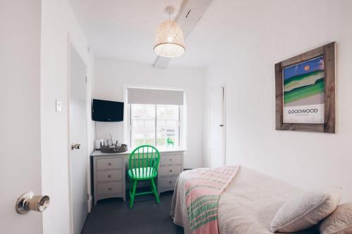 a bedroom with a bed and a desk and a green chair at The Old Store Guest House in Chichester