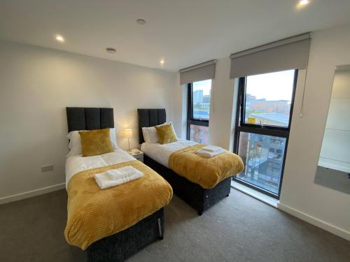 two beds in a room with a large window at Arden Gate Apartments in Birmingham