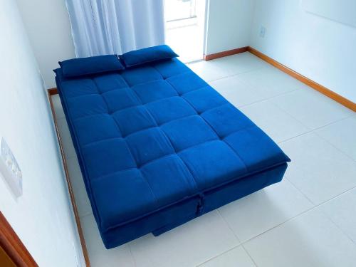 um sofá azul sentado num piso branco num quarto em Arejado com Localização Estratégica e Varandão - 203 em Cabo Frio