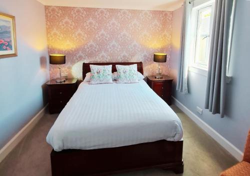 a bedroom with a large white bed with two lamps at Corriemar House in Oban