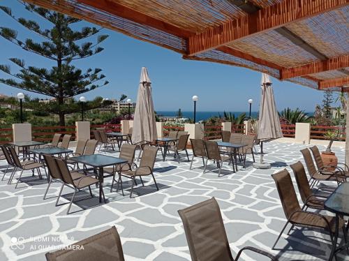 a patio with tables and chairs and umbrellas at Alexandros Studios in Kalamaki Chanion