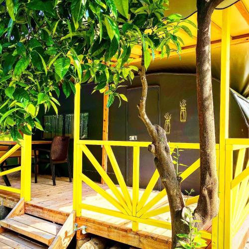 a yellow fence with a tree in front of a house at Kara Kedi Beach Bungalow in Cıralı
