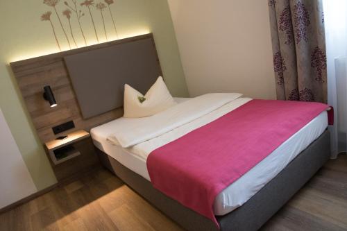 a bedroom with a large bed with a pink blanket at Hotel Bauer garni in Ingolstadt