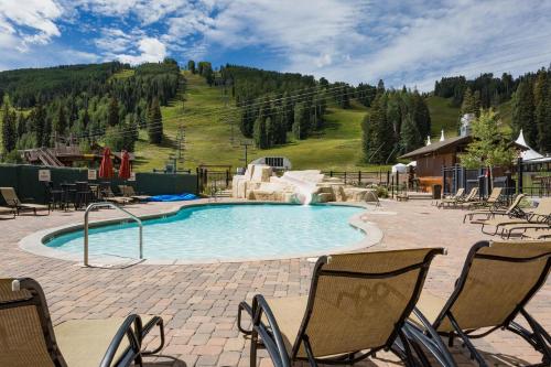 a swimming pool with chairs and a mountain in the background at Peregrine Point 106 in Durango Mountain Resort