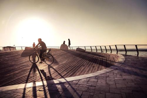 a person riding a bike on a boardwalk at Villa Brown Tel-Aviv, a member of Brown Hotels in Tel Aviv
