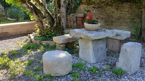 a garden with two stone benches and a flower pot at Chez Madgi et Jean-Mi in Froncles