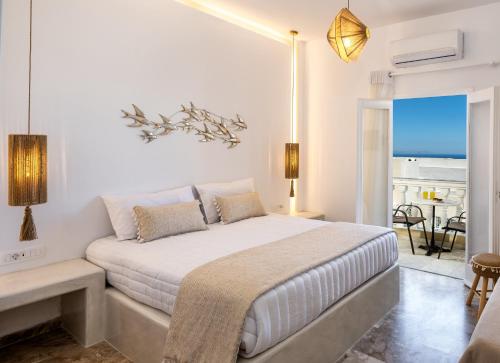 a white bedroom with a bed and a view of the ocean at Vinas Place City Center in Fira