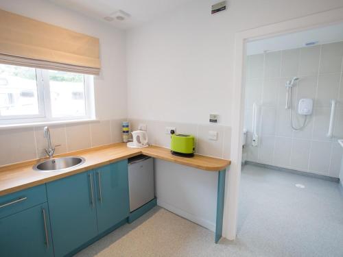 a kitchen with blue cabinets and a sink and a shower at Balcary House Hotel in Hawick