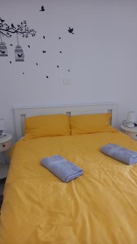 a yellow bed with two blue pillows on it at App Parenzana in Grožnjan