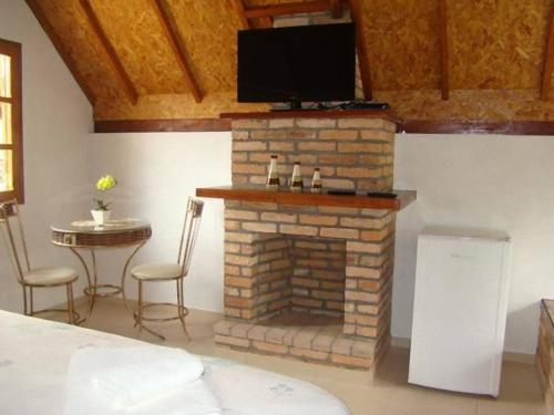 a living room with a fireplace with a tv on top at VELINN Pousadas Flor da Montanha in Monte Verde