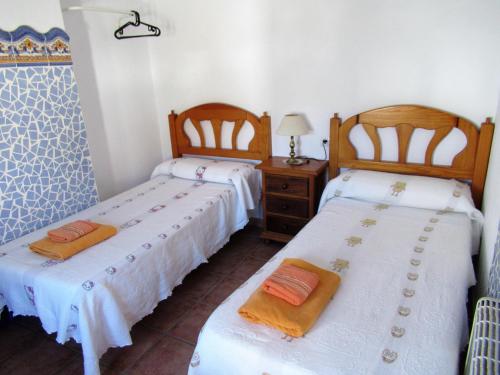 a bedroom with two beds and a table with a lamp at CASA CORRALON in Grazalema