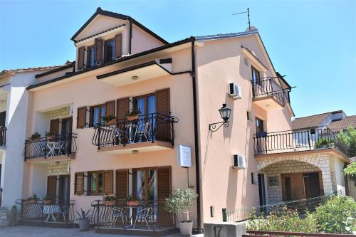 a large pink building with balconies and tables at Apartments & Rooms Ivana in Rovinj