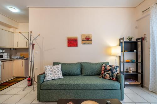 a living room with a green couch and a kitchen at Flat in excellent location with private parking in Athens