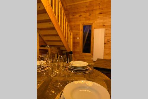 a dining room with a table with plates and glasses at Chalet L'Élégance - SPA - Serviettes - Peignoirs - Lits faits - Ménage inclus in Rochesson