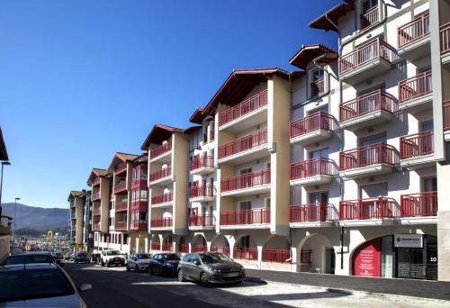 een gebouw met rode balkons en auto's geparkeerd op een straat bij Appartement spacieux et moderne - Tout confort in Hendaye