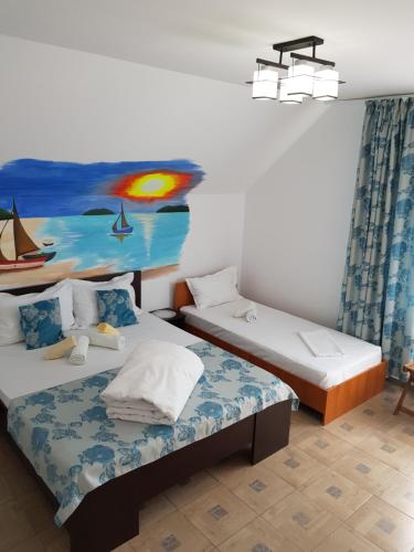 two beds in a room with a painting on the wall at EL Capitano - Mamaia Nord in Mamaia Sat/Năvodari
