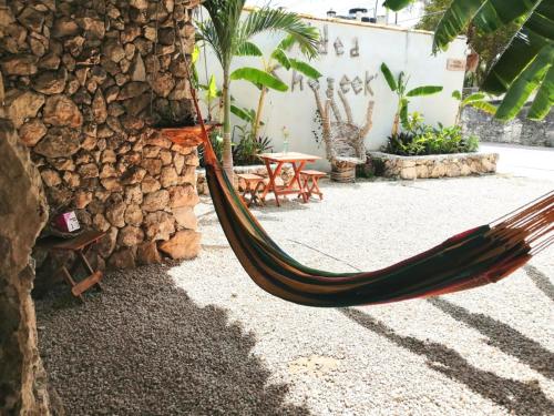 a hammock sitting next to a stone wall at Aldea Che-Eek , con acceso a un club de playa privado in Bacalar