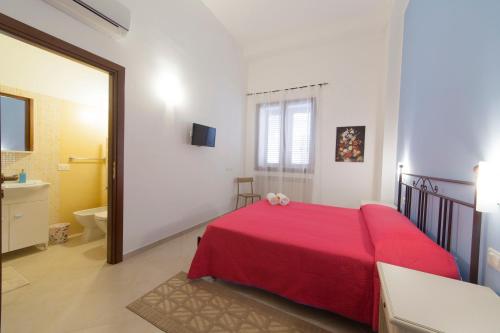 a bedroom with a red bed and a bathroom at Sole di Trapani in Trapani