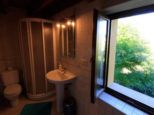 a bathroom with a sink and a toilet and a window at Apartamentos La Corona in Parres de Llanes