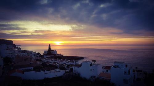 a sunset over a city with white buildings and the ocean at La Suite Calypso in Luz