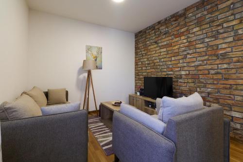a living room with two chairs and a brick wall at All Seasons Residence in Zlatibor