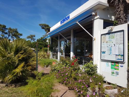 un panneau devant un bâtiment fleuri dans l'établissement Camping Le Puits de l'Auture, à Saint-Palais-sur-Mer