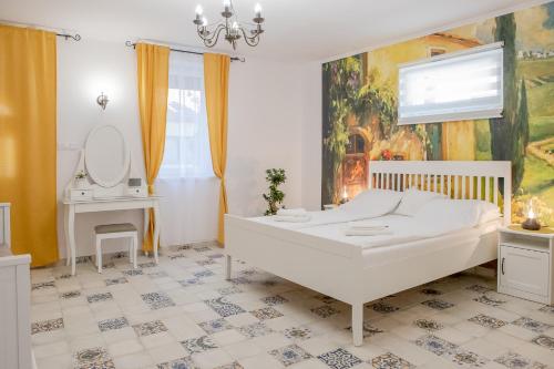 a white bedroom with a bed and a mirror at Jázmin Apartman in Makó