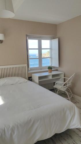 a bedroom with a bed and a chair and a window at Hotel Román in Naveces