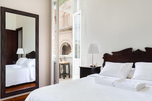 Santa Ana Suite & Rooms في لاس بالماس دي غران كاناريا: غرفة نوم بسرير أبيض ومرآة