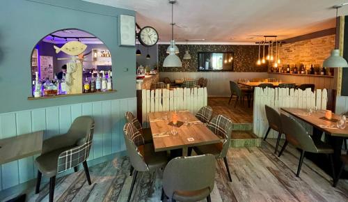 a dining room with tables and chairs and a clock at Stadthotel-Garni Smutje in Norden