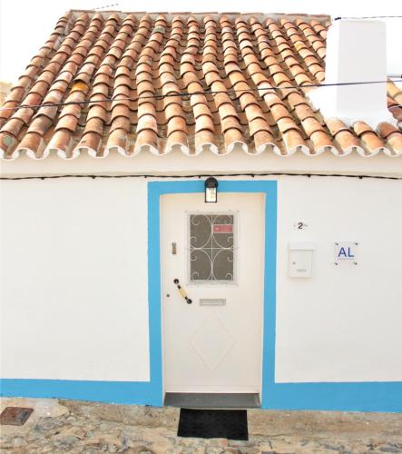 a building with a white door and a tile roof at Alma d'Outeiro in Monsaraz