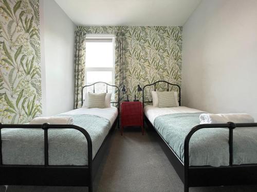two twin beds in a room with a window at Great located Victorian house with all amenities in Bristol