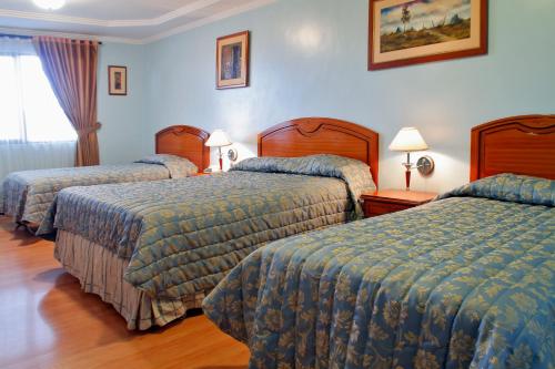 two beds in a hotel room with blue walls at Hotel Yanuncay in Cuenca