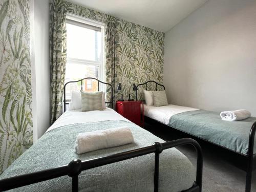 a bedroom with two beds and a window at Great located Victorian house with all amenities in Bristol