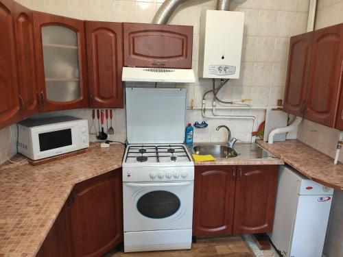 a kitchen with wooden cabinets and a stove top oven at Holiday Home u Tetiany in Kamianets-Podilskyi
