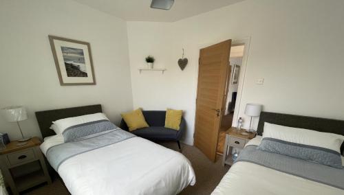 um quarto com 2 camas e uma cadeira em Clanrye House Guest Accommodation em Newry