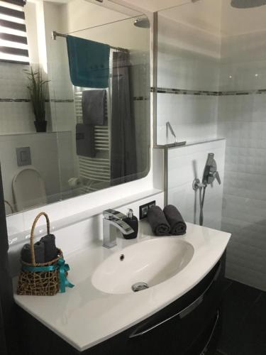 uma casa de banho com um lavatório branco e um espelho. em Petra Apartman em Tapolca