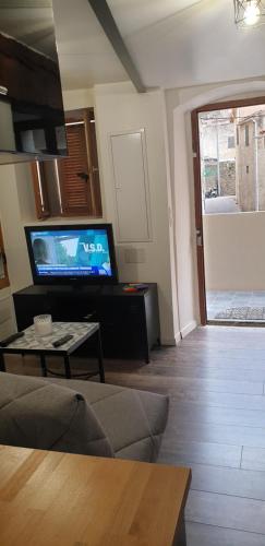 a living room with a flat screen tv and a couch at Charmant petit studio proche départ GR20 in Calenzana