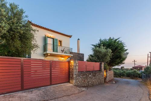 a red fence in front of a house at Lavender Garden Retreat - Secluded Seaside Getaway in Kotrónion