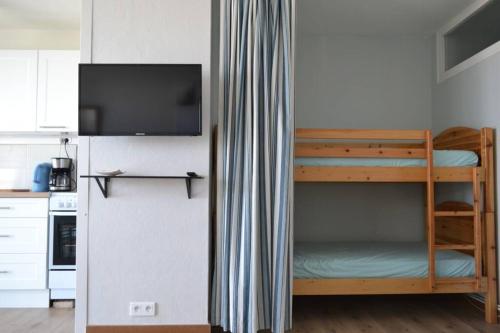 Cette chambre comprend des lits superposés, une télévision et une cuisine. dans l'établissement Appartement studio vue mer les pieds dans l'eau, à Saint-Jean-de-Monts