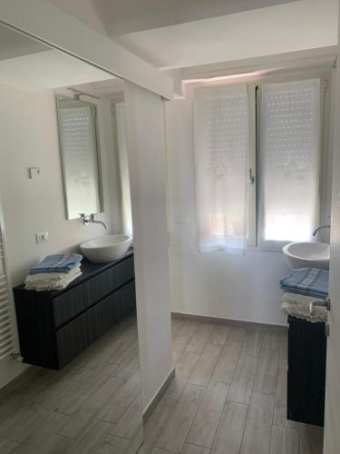 a white bathroom with two sinks and two mirrors at Casa Italia in Castelletto di Brenzone
