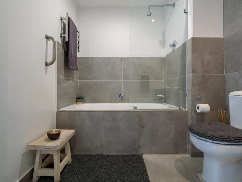 a bathroom with a tub and a toilet and a sink at Point Bay - Super Stylish for Less in Durban