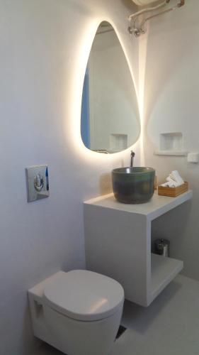 a bathroom with a sink and a toilet and a mirror at Tinos Sea View Residence in Agios Sostis