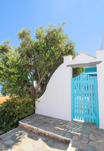 a blue gate on a white wall with a tree at Tinos Sea View Residence in Agios Sostis
